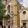 A historic cathedral in the middle of a town filled with people, buildings and trees